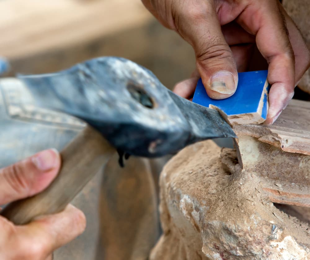 Artisan marocain qui taille un carreau de zellige