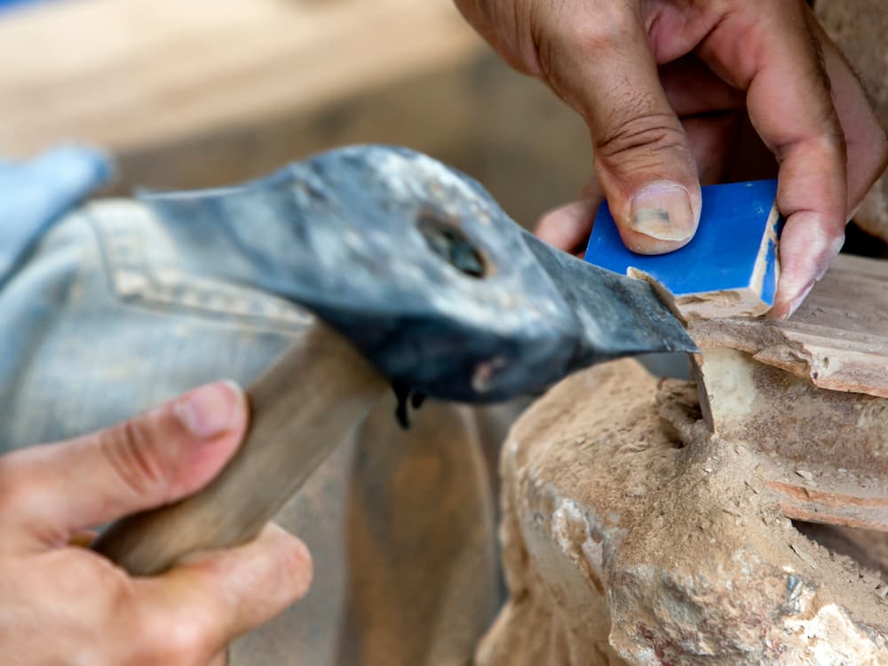 Artisan marocain qui taille un carreau de zellige